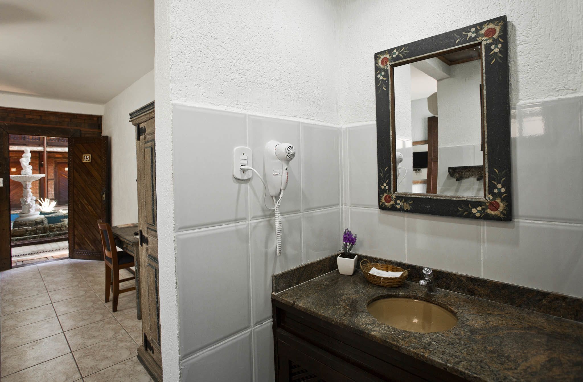 Un baño con lavabo, espejo y secador de pelo.