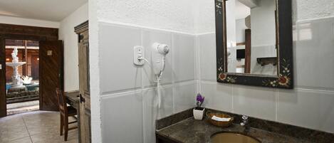 Un baño con lavabo, espejo y secador de pelo.