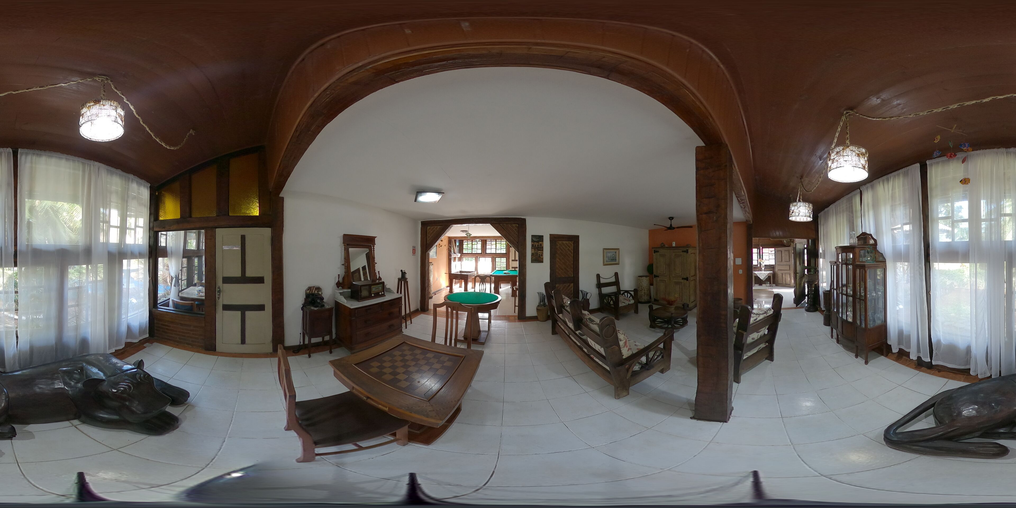 Une pièce spacieuse avec une haute porte en arc, des meubles en bois et une table de billard.