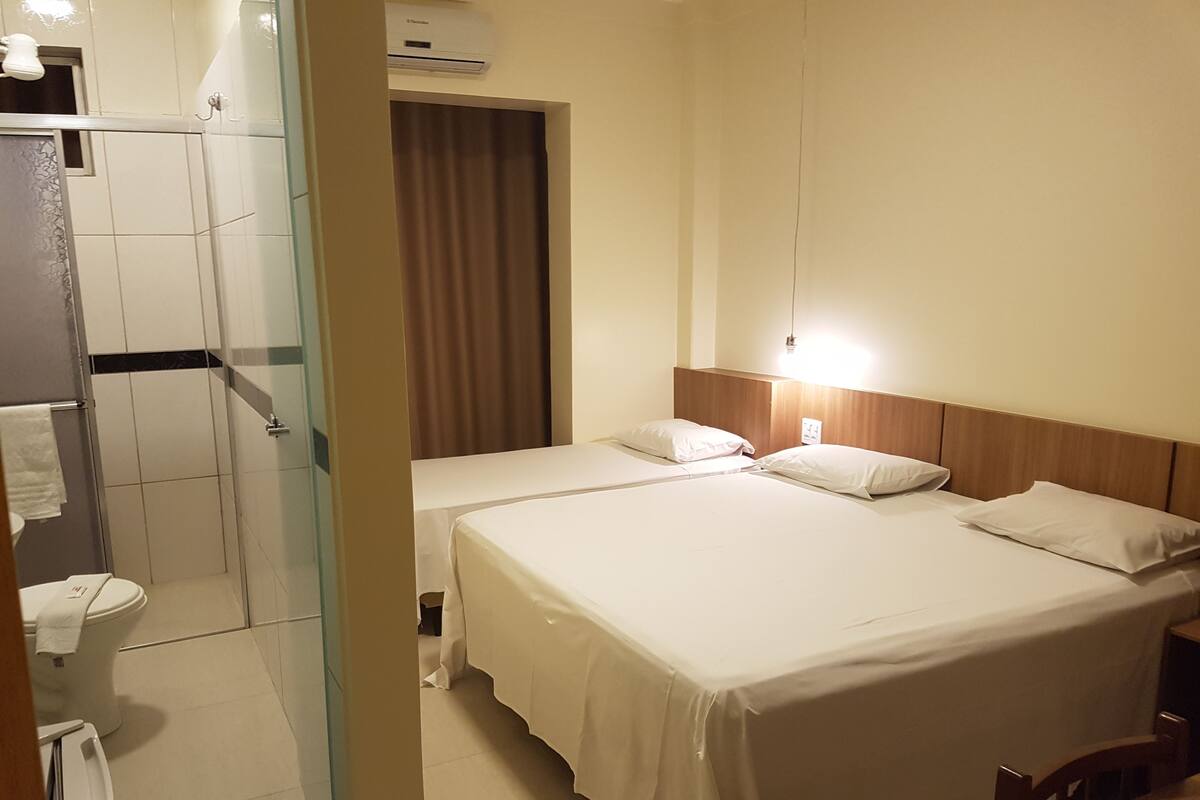 Une chambre d’hôtel avec deux lits, une douche, des toilettes et une salle de bain équipée d’un porte-serviettes.