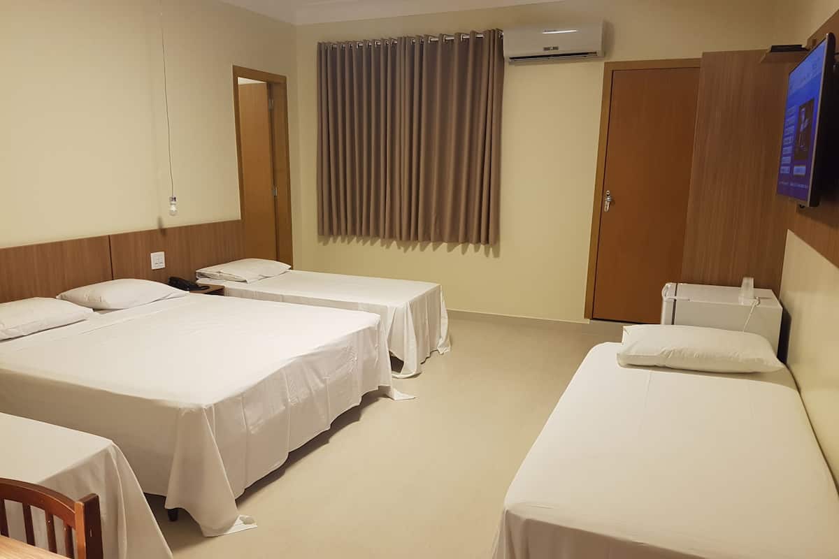 Une chambre d’hôtel avec deux lits simples, un bureau, une chaise, une table, une télévision et une armoire.