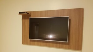 Een flatscreen televisie bevestigd aan een houten muur in een kamer met een wit bed en een witte muur.