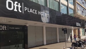 Een hotelgevel met 'Oft Place Hotel' aanduiding, gesloten luiken en een 'Rival' bord erboven.