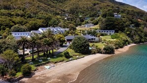 An aerial view of a coastal property with multiple houses, a beach, and lush greenery. - The Portage Resort (Portage)