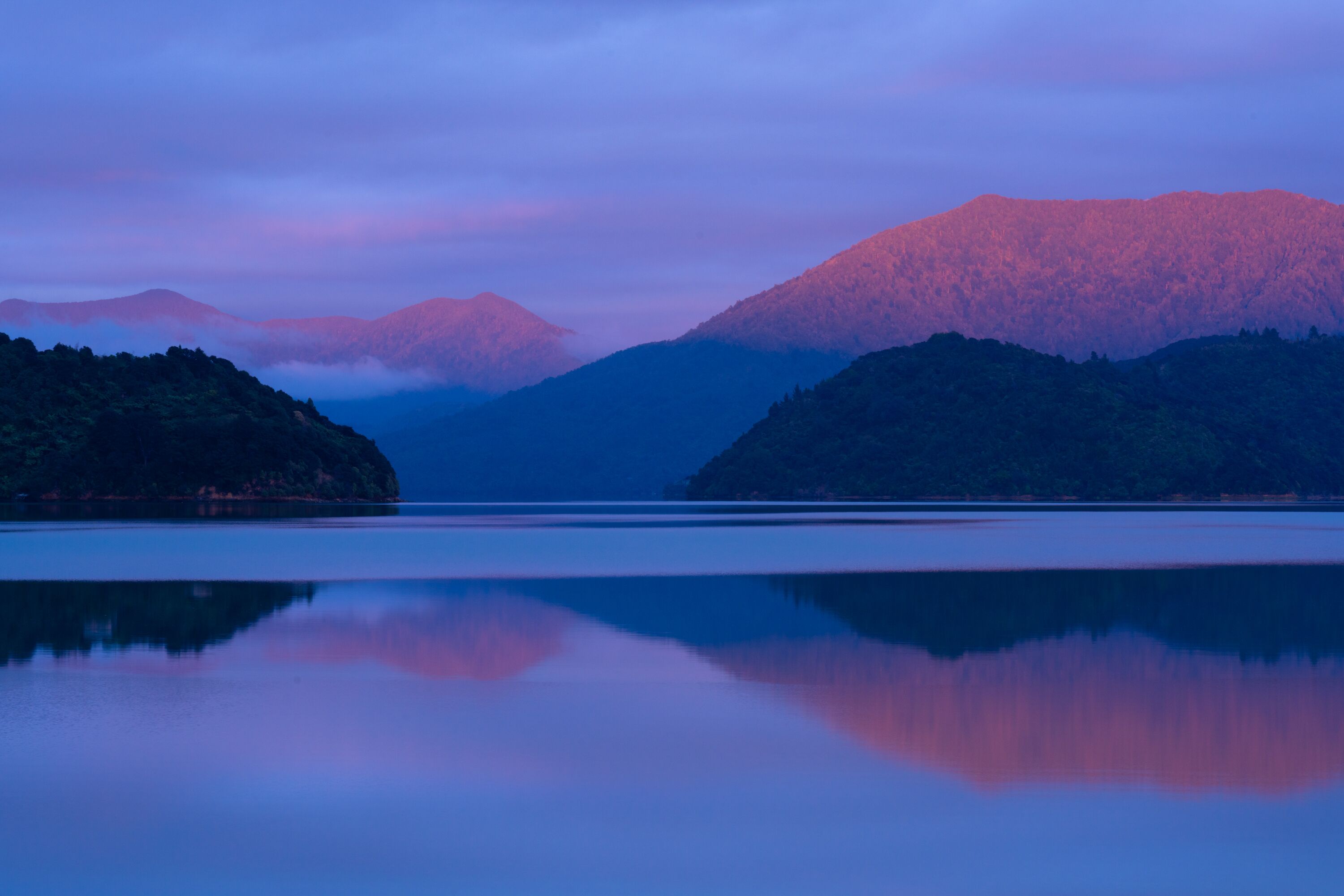 A calm lake with mountains in the background.