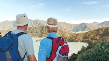 Two people hiking with backpacks, overlooking a mountainous landscape and a lake.