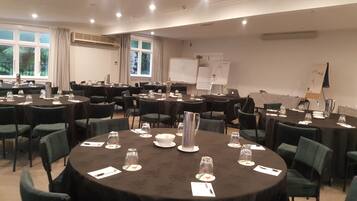 A conference room with multiple round tables, each set with chairs, water glasses, and a central silver pitcher.