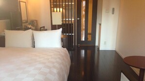 Une chambre d’hôtel avec un grand lit, une petite table ronde et une porte donnant sur une autre pièce.