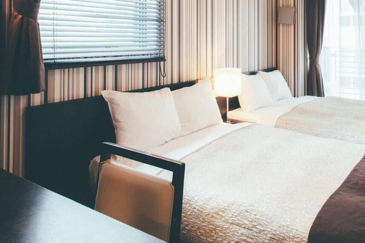 A hotel room with two beds, a desk, and a chair.