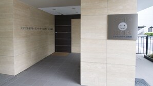 L’entrée d’un immeuble, avec une enseigne indiquant « Smile Hotel » et du texte en japonais.