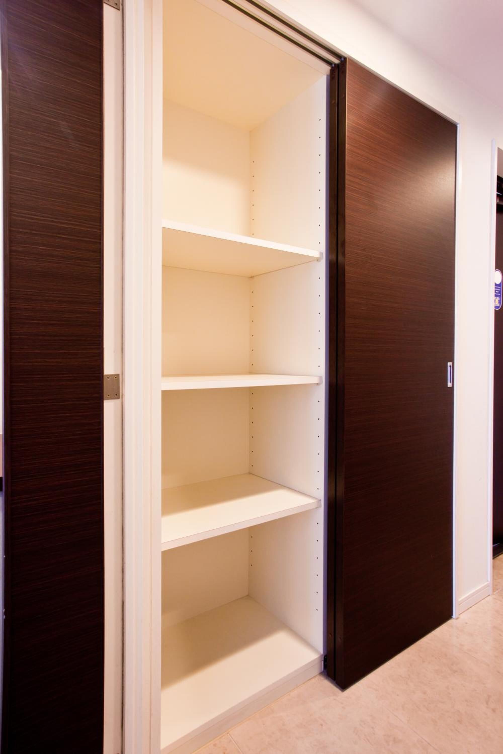A closet with three shelves and a sliding door.