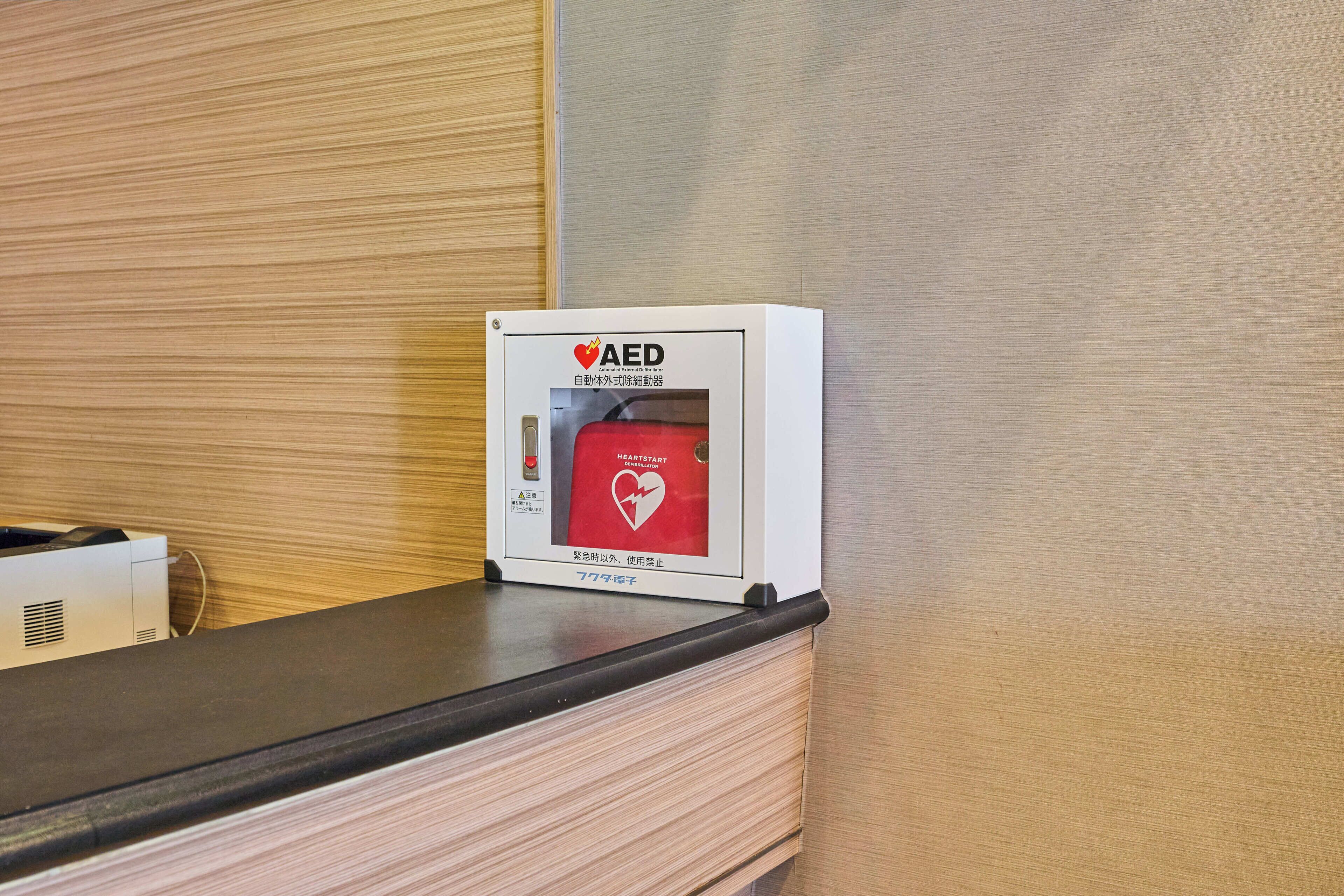 An AED device on a counter with a wooden panel wall in the background.