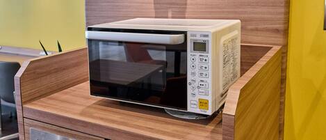 A microwave oven placed on a wooden counter with a digital display and control panel.