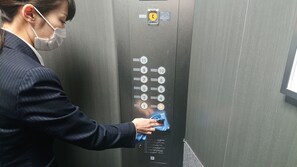 A person cleaning an elevator control panel. - Smile Hotel Tokyo Nihonbashi (Tokyo)
