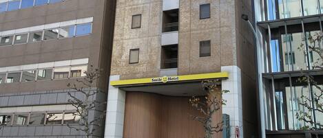 Un immeuble arborant une enseigne « Smile Hotel », avec de nombreux étages et une façade moderne.