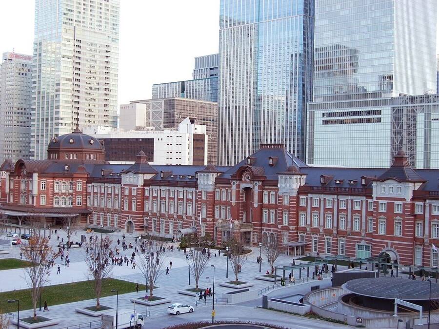 Um edifício histórico com cúpula central e arquitetura simétrica, rodeado por edifícios modernos altos.
