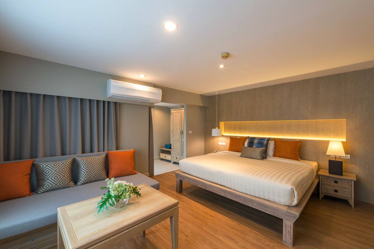 Une chambre d’hôtel moderne équipée d’un lit, d’un canapé, d’une table de chevet et d’un appareil de climatisation.