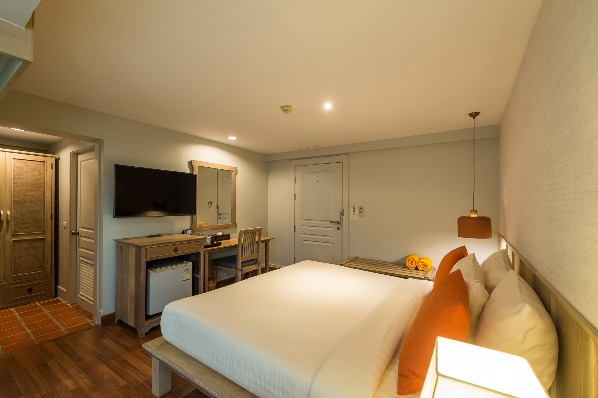 Una habitación de hotel con una cama, un escritorio con una silla, un televisor y un armario.