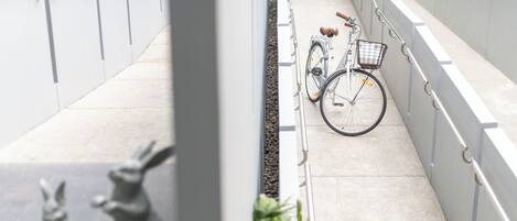 A bicycle parked next to a white railing, with a small basket attached to the front.