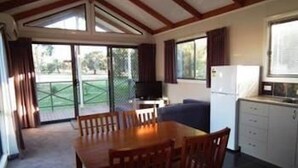 A compact kitchen with a dining area, a television, and a refrigerator. - Cobram Barooga Golf Resort (Barooga)