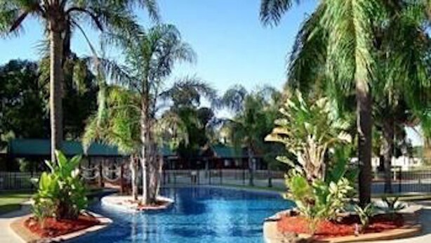 A swimming pool surrounded by palm trees and a covered area. - Cobram Barooga Golf Resort (Barooga)