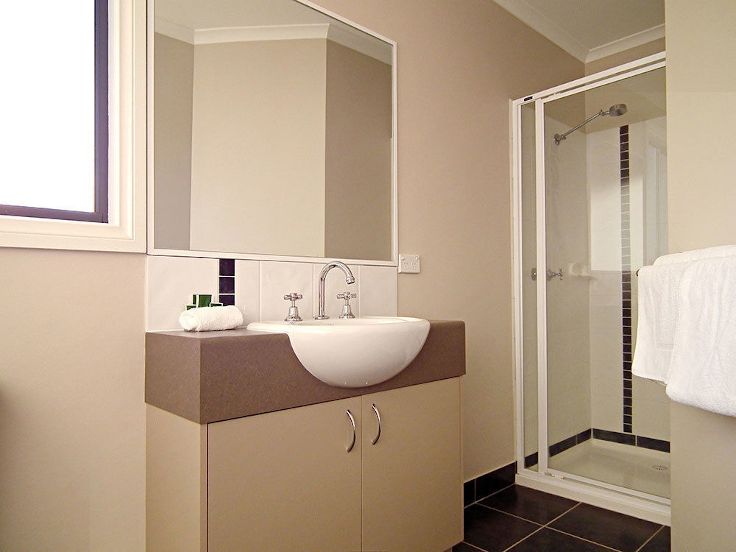 Un bagno moderno con uno specchio grande, un lavandino e una doccia.