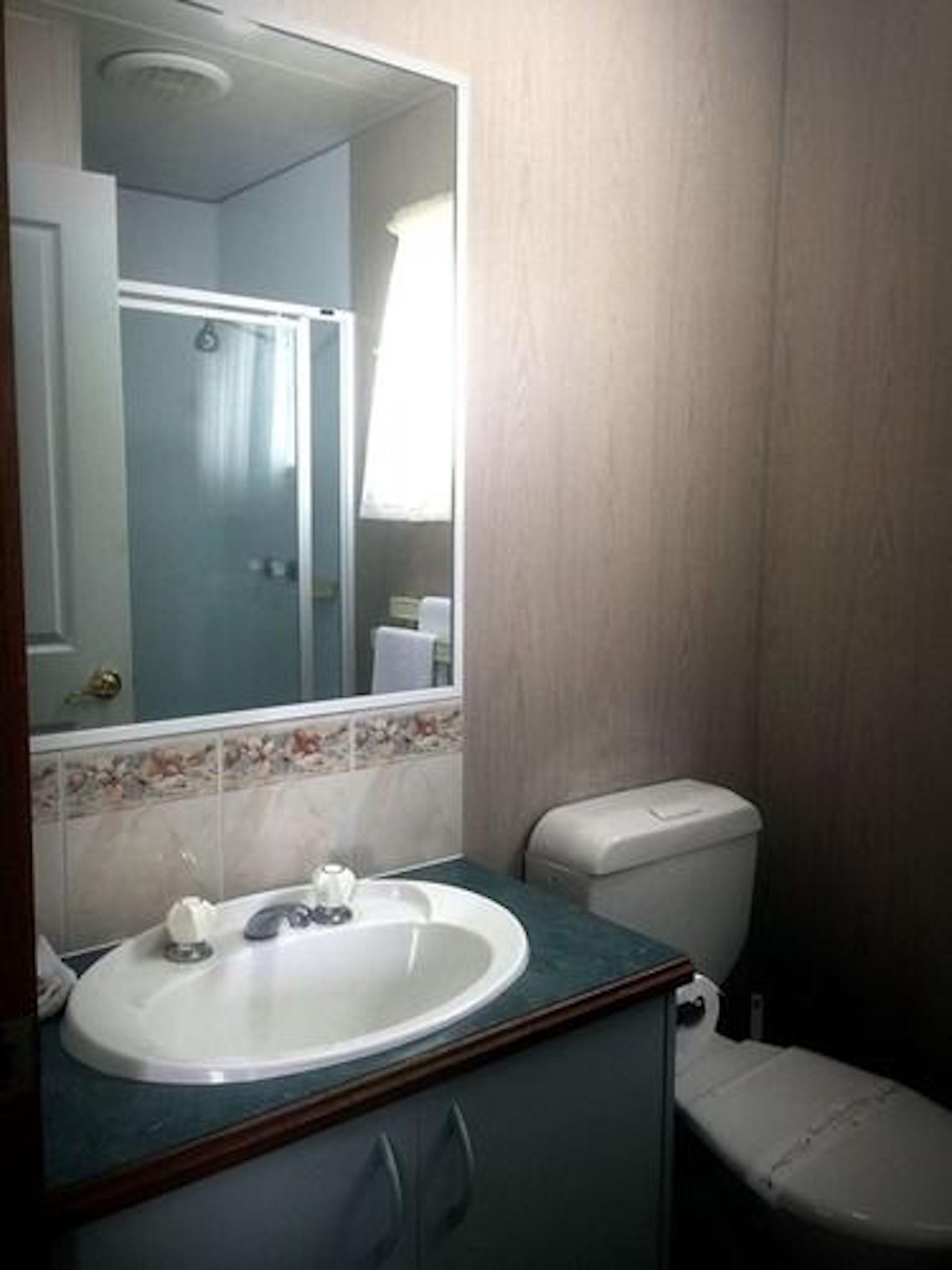 Een badkamer met een wastafel, toilet en spiegel.