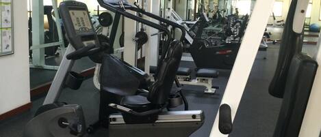 A gym with cardio machines, weight machines, and mirrors on the walls.