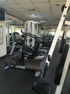 Une salle de sport équipée de machines de cardio, de machines de musculation et de miroirs aux murs.