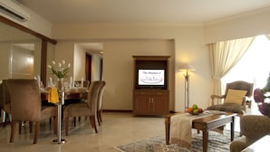 Habitación de hotel con comedor, televisión, lámpara y sofá.