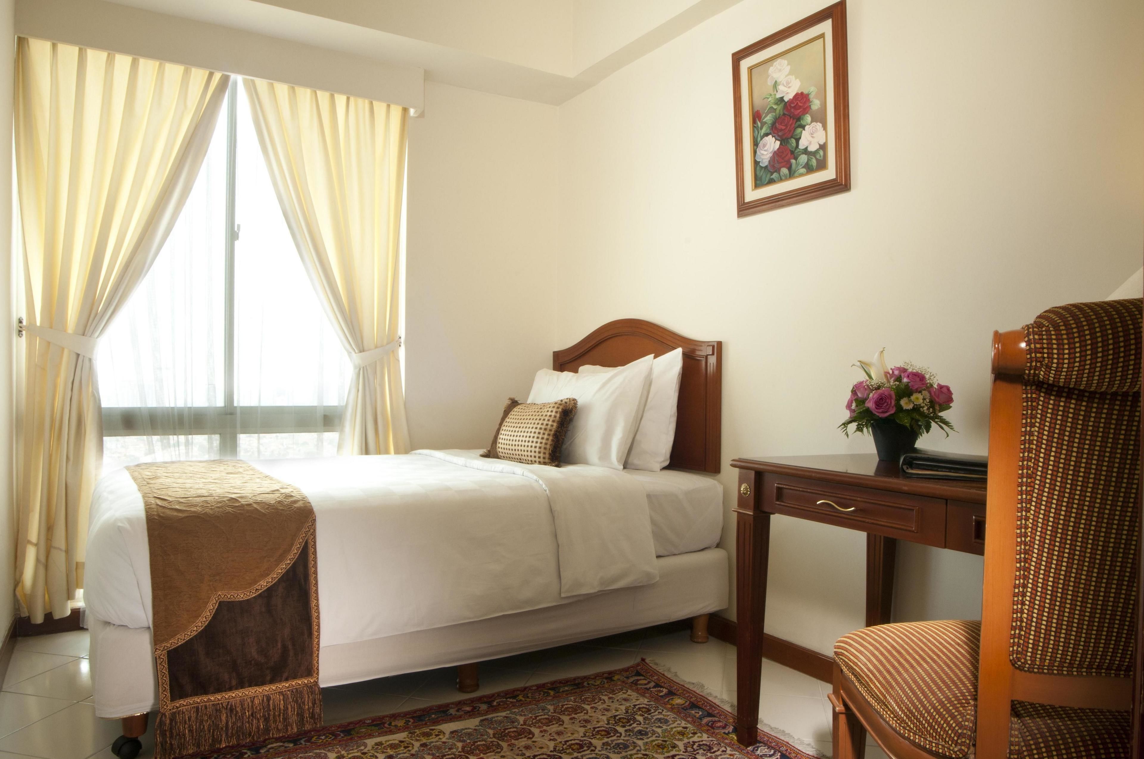 Une chambre d’hôtel bien rangée, avec un lit, un bureau et une chaise.