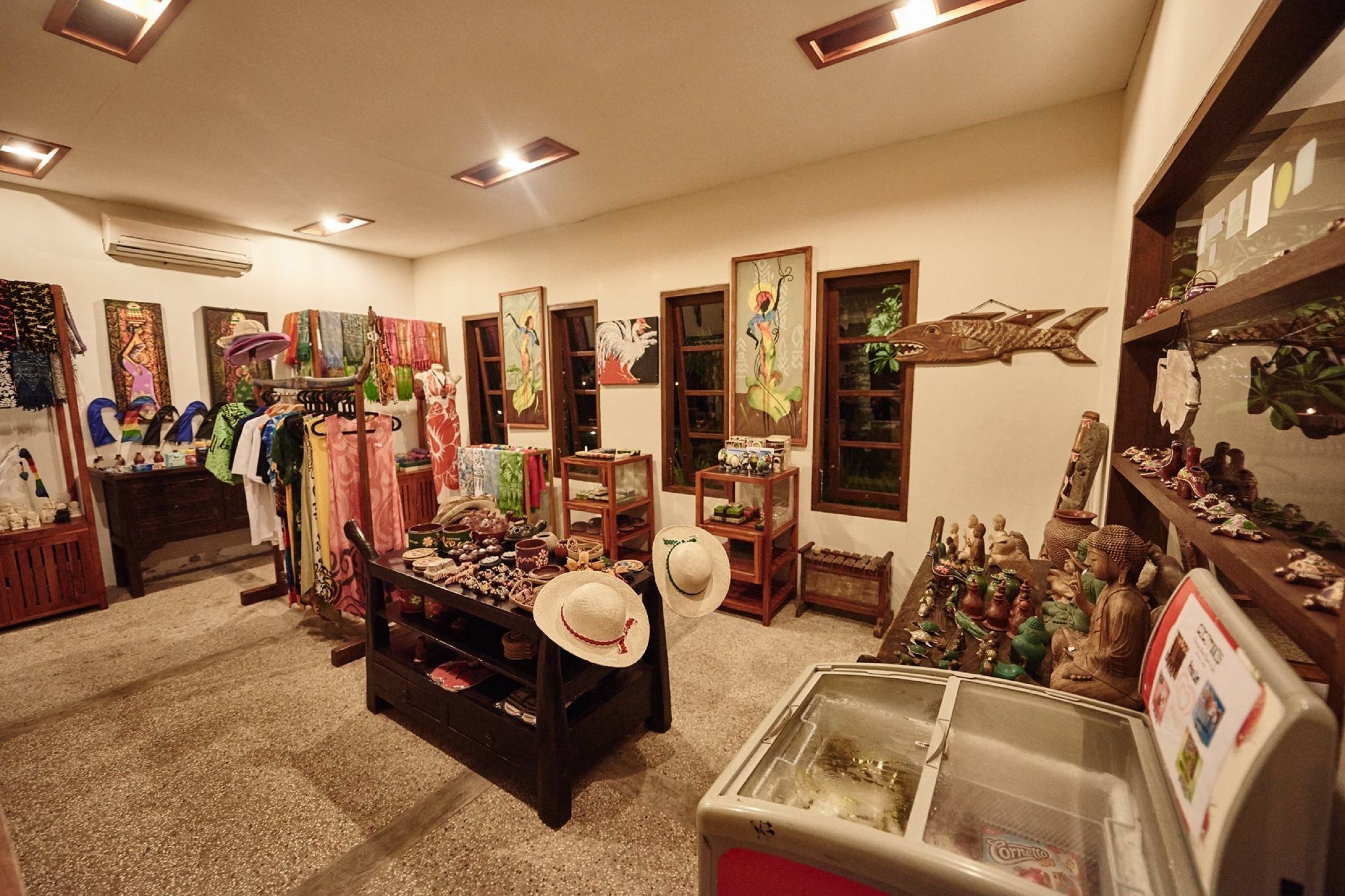 Una habitación con una variedad de objetos expuestos, incluyendo sombreros, figurillas y adornos. Hay estanterías con varios artículos y una vitrina con puerta de vidrio.