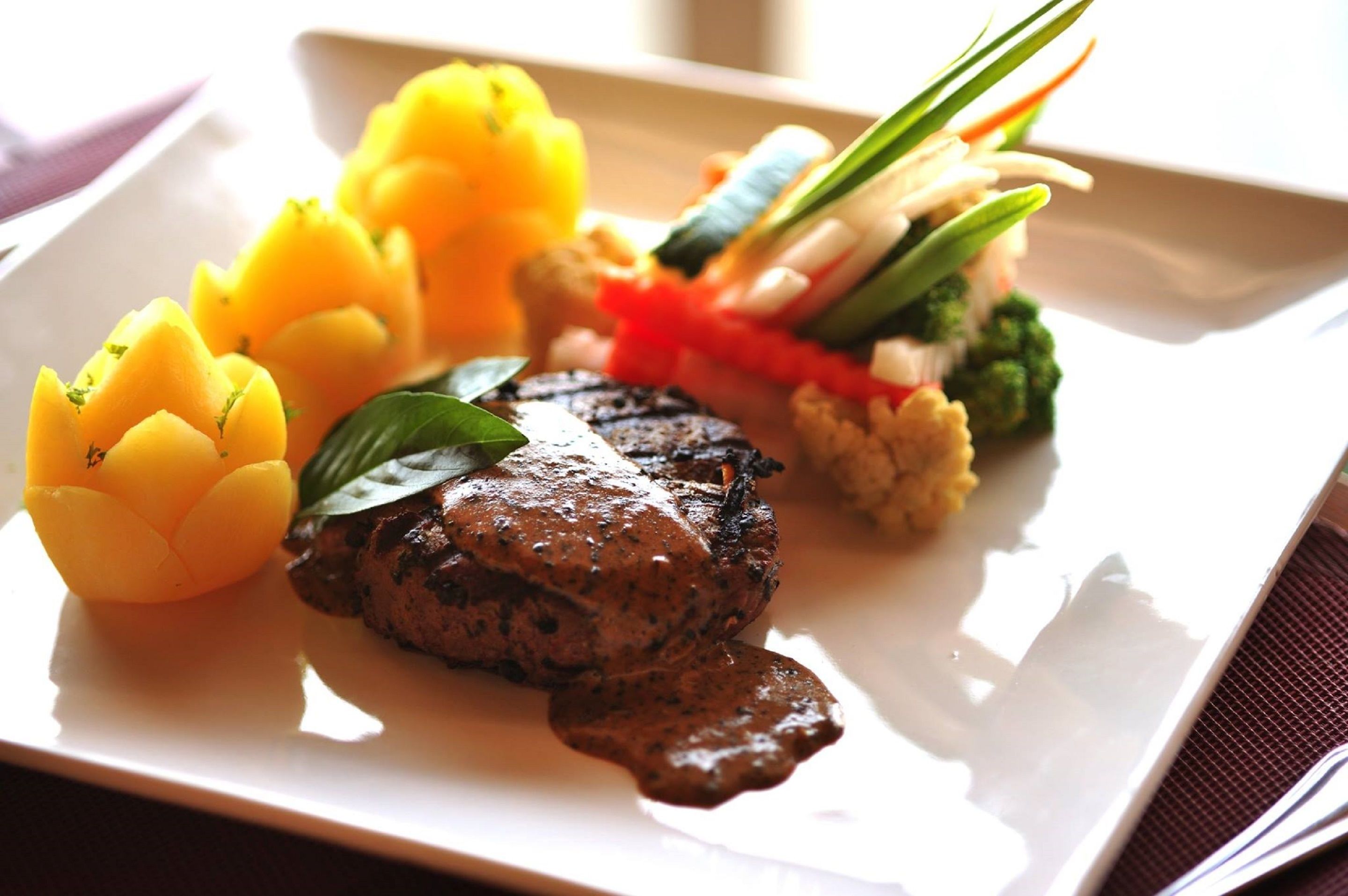 A plate with a steak, yellow squash, and a vegetable medley.