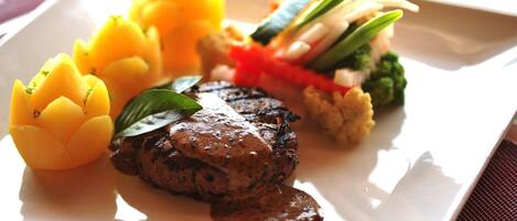 Une assiette comprenant un steak, des courgettes jaunes et un assortiment de légumes.