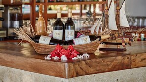 A bar area with bottles of wine and a decorative ship model. - Cocotinos Sekotong, a Boutique Beach Resort & Spa (Sekotong Barat)