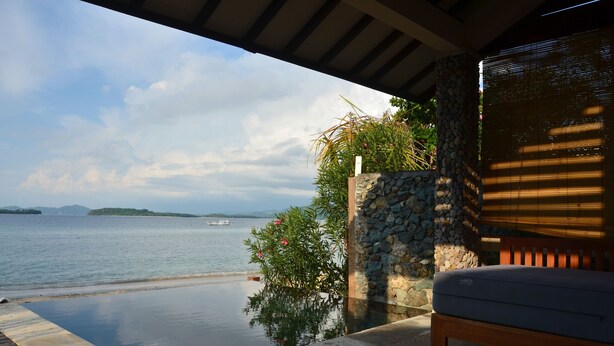 A balcony with a view of the sea, a stone wall, and a bench. - Cocotinos Sekotong, a Boutique Beach Resort & Spa (Sekotong Barat)