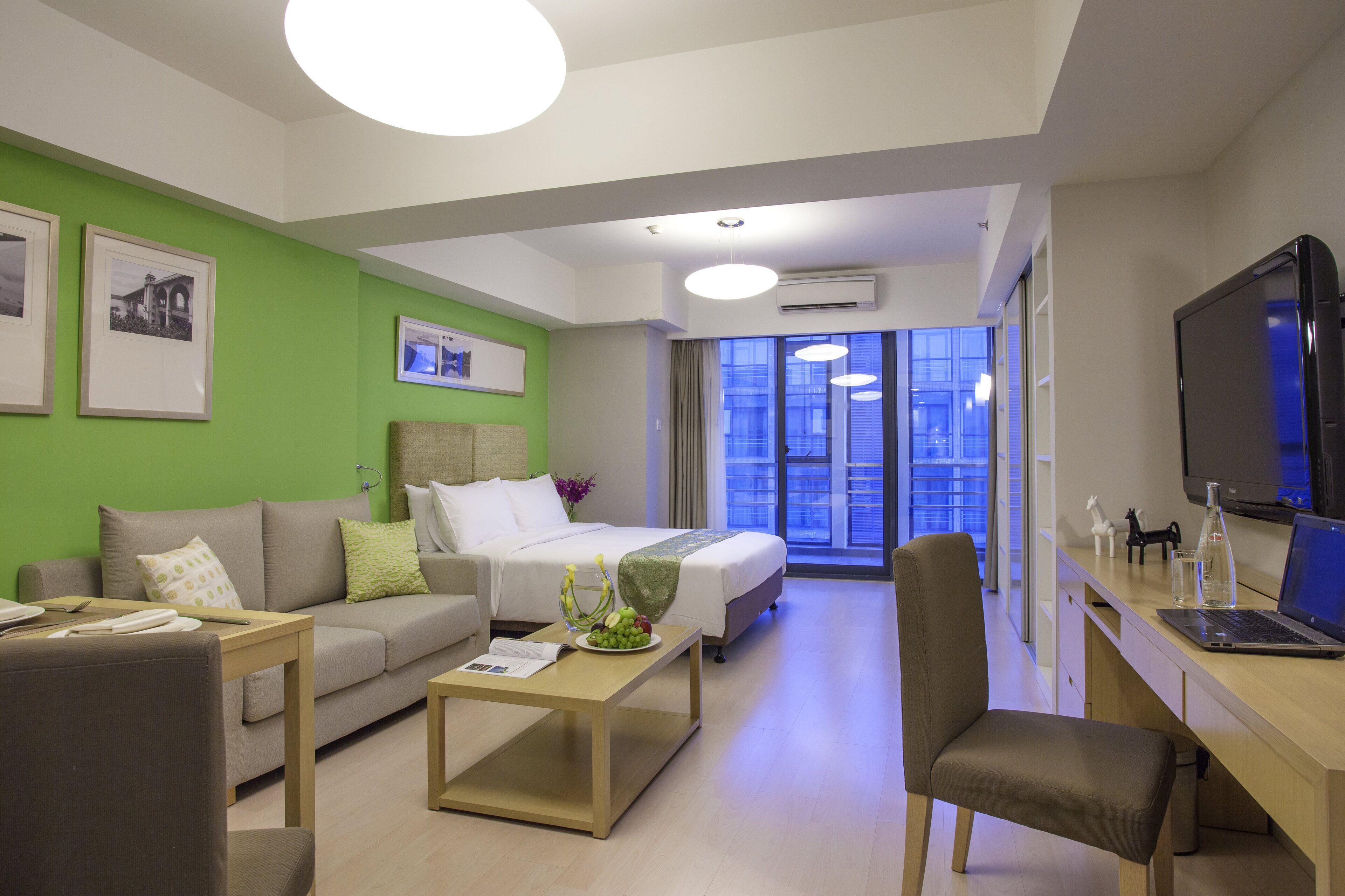 Een moderne hotelkamer met een bed, een bank, een bureau en een televisie.