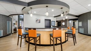 A modern bar area with a curved counter, multiple bar stools, and pendant lighting. - Comfort Suites New Bern near Cherry Point (New Bern)