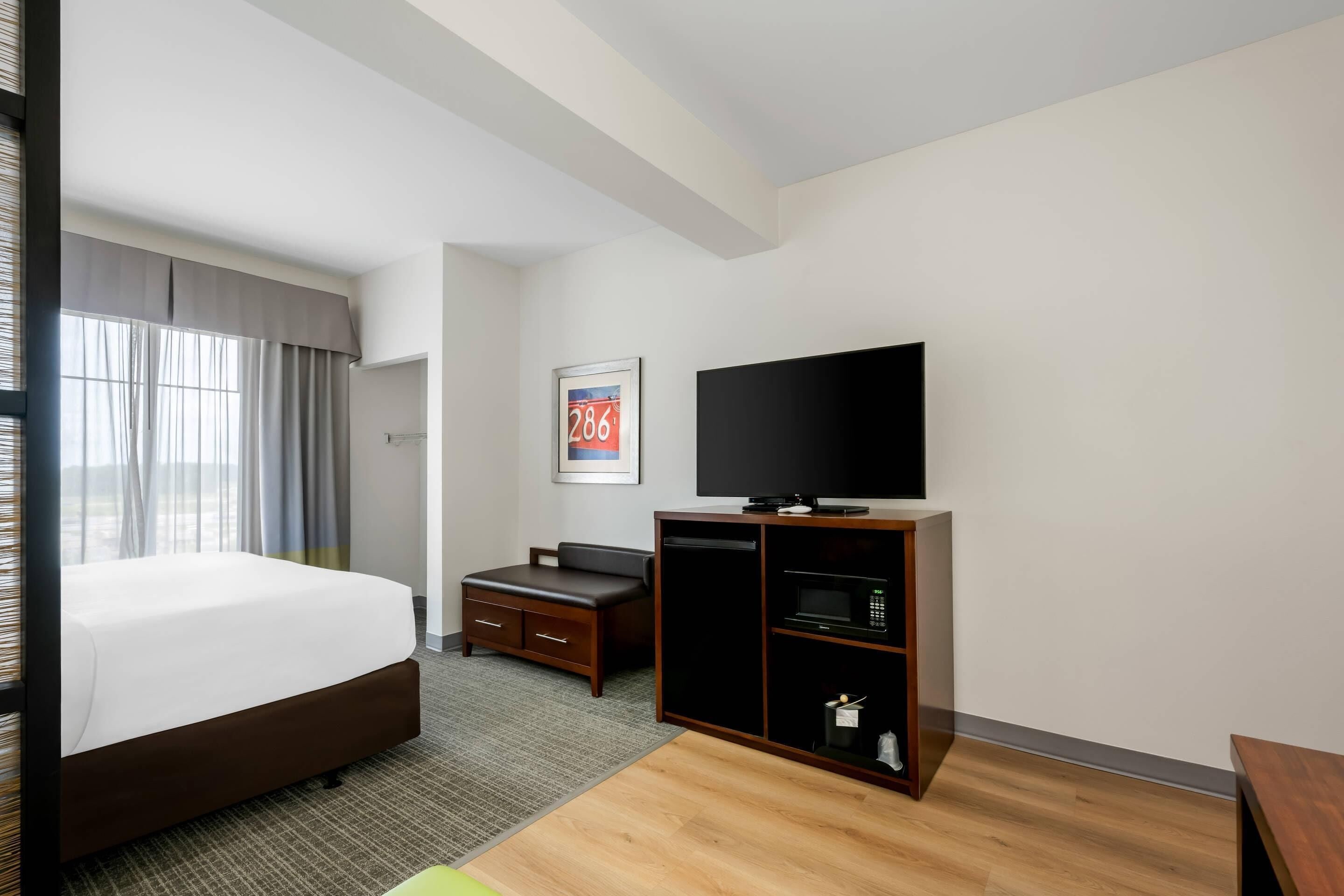 A hotel room with a bed, a television, a desk, and a microwave.