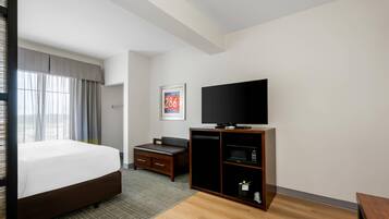 A hotel room with a bed, a television, a desk, and a microwave.