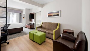 Habitación de hotel con cama, sofá, escritorio y televisión.
