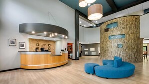 A reception area with a curved wooden desk, a blue seating area, and a wall with a wooden panel design. - Comfort Suites New Bern near Cherry Point (New Bern)