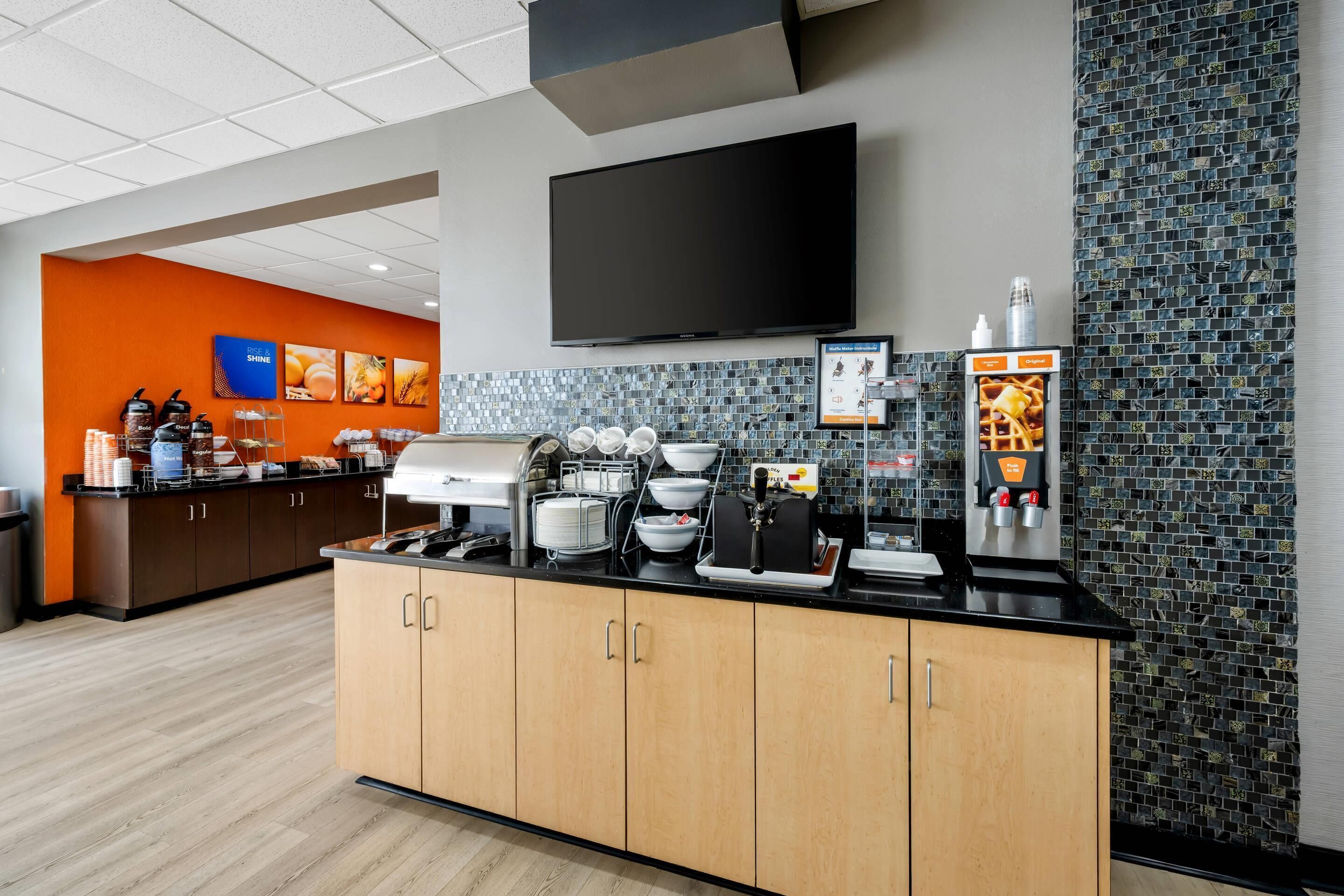 Una cocina moderna con televisor de pantalla plana, cafeteras y un fabricante de gofres.