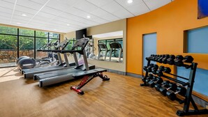 Un gimnasio con cintas de correr, una bicicleta estática y un soporte para pesas.