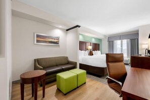 Une chambre d’hôtel avec un lit, un canapé, un bureau et une petite table.
