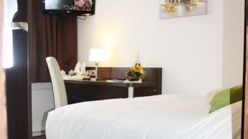 Een hotelkamer met een bed, een bureau met lamp, een televisie en kunst aan de muur.