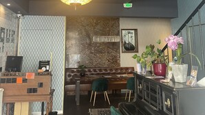 Interior de restaurante con candelabro, asientos, piano y mostrador de recepción.