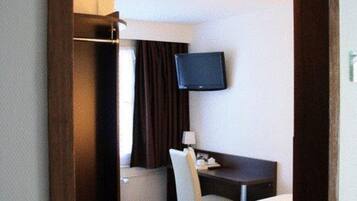 A hotel room with a bed, a desk, a television, and a wardrobe.