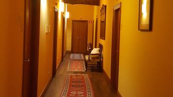 En hall med synliga träbjälkar, gula väggar och mönstrade mattor.