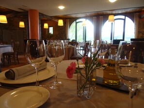 A dining area with tables set for a meal, featuring wine glasses, plates, and a vase with flowers. - Hotel Restaurante Usategieta (Oiartzun)